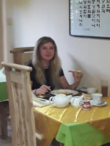 Kobieta siedząca przy stole jedząca kawałek jedzenia w obiekcie Victory colombo w Kolombo