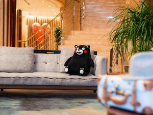 un oso panda de peluche sentado en un sofá en Mitsui Garden Hotel Kumamoto, en Kumamoto