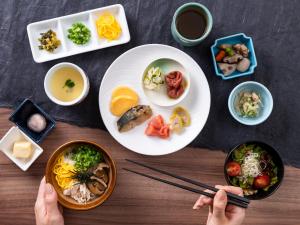 Mitsui Garden Hotel Kumamoto في كوماموتو: طاولة مع أطباق من الطعام والناس الذين يحملون عيدان الطعام