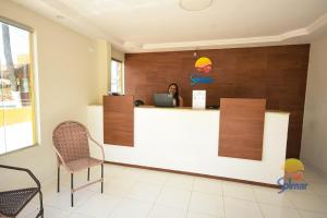 a woman sitting at a counter in a waiting room at Pousada Solmar in Japaratinga
