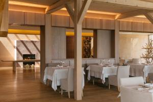 a restaurant with white tables and chairs and a fireplace at Vigilius Mountain Resort in Lana