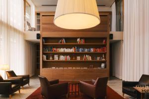 a living room with chairs and a book shelf at Vigilius Mountain Resort in Lana