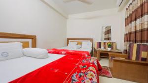 2 Betten in einem Zimmer mit einer roten Decke in der Unterkunft Hotel New Royal Palace Dhanmondi in Dhaka