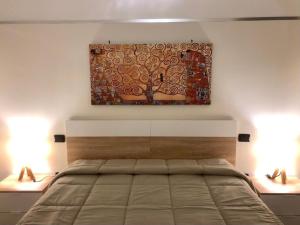 1 dormitorio con 1 cama con una pintura en la pared en Happy Loft Salento, en Cellino San Marco
