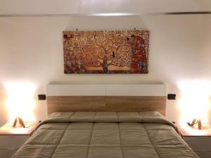 a bedroom with a bed with a painting on the wall at Happy Loft Salento in Cellino San Marco