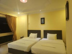 2 camas en una habitación con paredes amarillas en SOMA HOTEL, en Phnom Penh