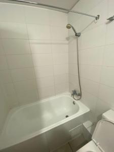 baño blanco con bañera y aseo en Habitacion Grande con baño privado en departamento compartido en Santiago