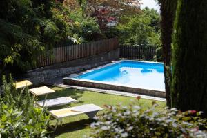 een zwembad in een tuin met 2 stoelen en een tafel bij Garni Juval in Tirolo