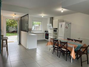 cocina y comedor con mesa y sillas en Duplex NEUF 90 m2 - 3 chambres, avec jardin à Sartrouville, en Sartrouville