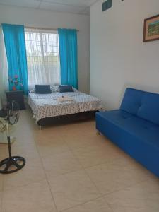 a bedroom with two beds and a blue couch at Casa Campestre con Piscina Jacuzzi y Golfito in Villavicencio