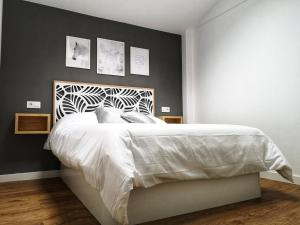 1 dormitorio con 1 cama blanca grande y pared negra en Cabanela Maitia Apto Matteo Barbacoa, Jacuzzi solo en Apto Deluxe, en Ribadeo