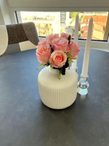 un jarrón blanco con rosas rosas y dos velas en Rosie apartment, en Nova Gorica