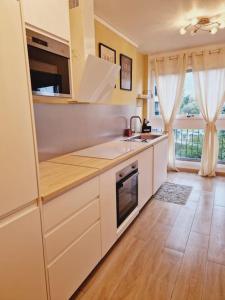 uma cozinha com armários brancos e piso em madeira em Appartement neuf proche parc de Versailles + parking em Le Chesnay