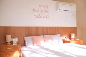 ein Schlafzimmer mit einem Bett mit einem Happy Place Schild an der Wand in der Unterkunft Ashamaya Belitung (Dome Glamping Site) in Pasarbaru