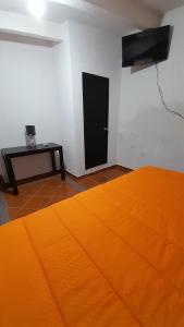 een kamer met een oranje bed en een zwarte deur bij Posada El Refugio in Mineral de Pozos