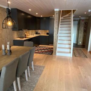 a kitchen and dining room with a table and a staircase at Kikut Panorama, Geilo - sleeps 9pax, ski in/out - Modern 2 floor apart in Geilo