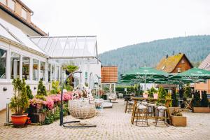 eine Terrasse mit Tischen, Stühlen und grünen Sonnenschirmen in der Unterkunft Hotel & Restaurant Olio é Pane in Enzklösterle