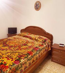 a bed with a colorful quilt and a clock on the wall at Vallecorsa city in Vallecorsa