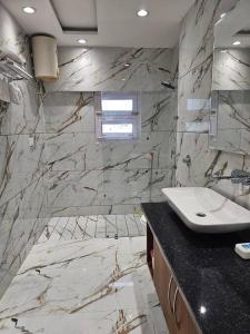 a bathroom with a sink and a marble wall at Ankhi's Villa with Parking in Amritsar