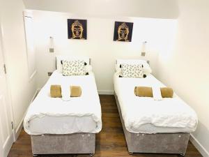 two beds in a small room with white walls at Buckinghamshire Elegant Studio in Buckinghamshire