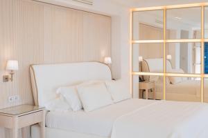 a white bedroom with a white bed and a mirror at Hotel Mamela in Capri