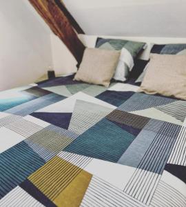 uma cama com um edredão colorido e almofadas em Charmandy em Cany-Barville