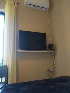 a flat screen tv on a wall in a bedroom at Ο κόκορας in Artemida