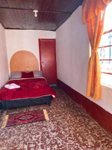 a bedroom with a red bed and a window at Habitación Amapola in Girardota