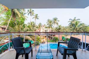 a balcony with two chairs and a swimming pool at Treebo Trend Gulmohar Beach Resort in Calangute