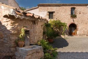 a stone building with a door and a yard at Masia Sapera in Pontons