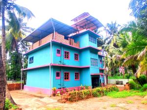a blue building with palm trees in front of it at Benirosa Homestay Apartments 2 in Velcao