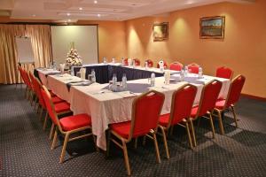 a conference room with a long table and red chairs at Kakiri Gardens and Hotel in Wakiso