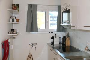 a kitchen with white cabinets and a sink and a window at La Suite Swiss Alps in Davos