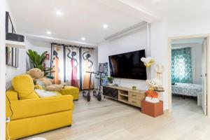 a living room with a yellow couch and a television at LUJO: Parking, Proyector, Maquinita y Patinetes in Oviedo