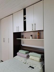 a bedroom with white cabinets and a bed with towels at Vilage Taipan 02 - Praia Stella Maris in Salvador