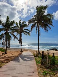 um caminho de madeira que leva a uma praia com palmeiras em Vilage Taipan 02 - Praia Stella Maris em Salvador