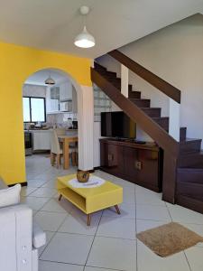 a living room with a staircase and a yellow table at Vilage Taipan 02 - Praia Stella Maris in Salvador