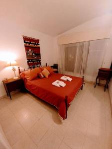 1 dormitorio con 1 cama roja y 2 toallas en Comodo y amplio Chalet de Montaña con Chimenea en Los Cocos