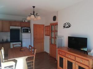 een keuken met een houten tafel en een televisie op een aanrecht bij Orcières Appartement au pied des pistes avec piscine in Orcières