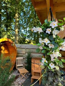 un jardín con una cabaña de madera con un banco y flores en CHALET HARMONY prive WELLNESS, en Putten