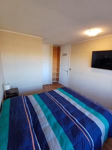 um quarto com uma cama com um cobertor azul e listrado em Departamento Central en Calama em Calama