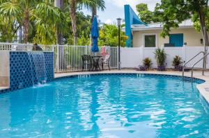 a swimming pool with a fence and a house with palm trees at Seaside Villas in Fort Lauderdale