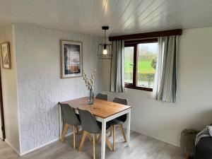 a dining room with a wooden table and chairs at Vrijstaand chalet met veel buitenruimte en veranda in Zuid-Scharwoude