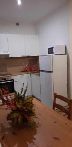 una cocina con electrodomésticos blancos y una mesa con un jarrón de flores en Sleepy3city Apartments 10 Lutego 23 en Gdynia