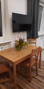 a wooden table with two chairs and a television on a wall at Sleepy3city Apartments 10 Lutego 23 in Gdynia