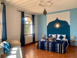 Dormitorio azul con cama y ventana en Le Domaine d'Eden - Villa luxueuse, piscine, spa et personnel, en Essaouira