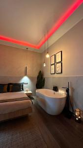 1 dormitorio con bañera y 1 cama con iluminación roja en Falco Suite Apartment en Nápoles