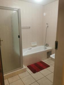 a bathroom with a shower and a tub and a toilet at Rose Guest House in Pretoria