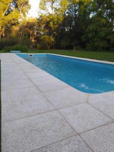 una piscina con una pasarela de hormigón junto a ella en Quinta Los Cardales en Los Cardales