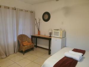 Zimmer mit einem Bett und einem Schreibtisch mit einer Mikrowelle in der Unterkunft Rose Guest House in Pretoria